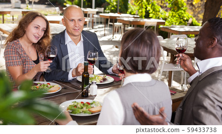 Four friends having lunch on the terrace open-air restaurant 59433738