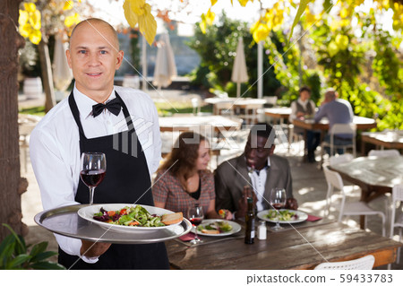 Adult waiter who is standing with order at summer cafe 59433783