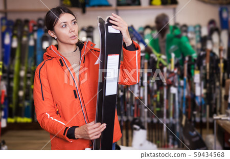 Focused young female skier looking for new skis Focused young female skier looking for new skis 59434568