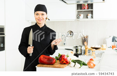 Portrait of woman cook who is standing with devices on her work place in the kitchen 59434743