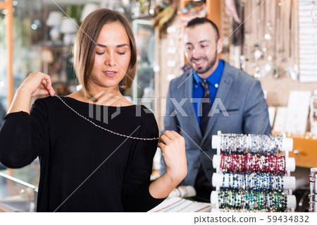 Female consumer trying chainlet with pendants 59434832