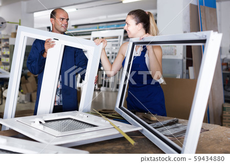 Workers in overalls assembling pvc windows at workshop Workers in overalls assembling pvc windows at workshop 59434880