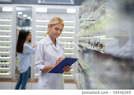 Woman working in optical store making notes while counting glasses 59436269