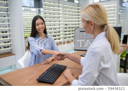 Woman greeting her ophthalmologist before visual control Woman greeting her ophthalmologist before visual control 59436321