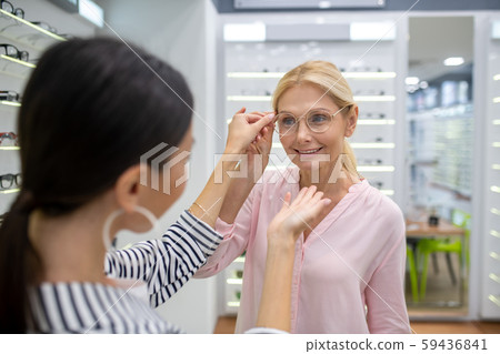 Gorgeous woman trying to choose ideal shape of glasses frame 59436841