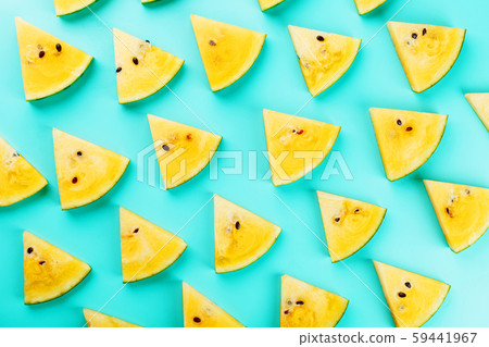 Pattern of slices of fresh yellow watermelon on a blue background. View from above. Free space 59441967