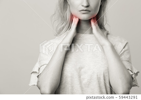 Female checking thyroid gland by herself. Close up of woman in white t- shirt touching neck with red Female checking thyroid gland by herself. Close up of woman in white t- shirt touching neck with red 59443291