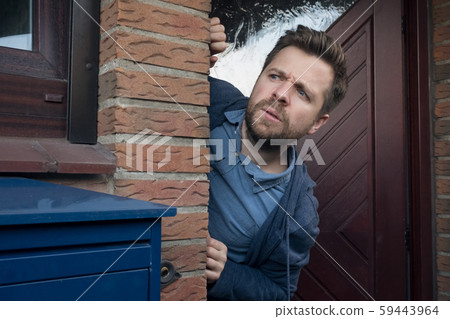 Handsome young man opening door looking on what his neighbor is doing. Handsome young man opening door looking on what his neighbor is doing. 59443964
