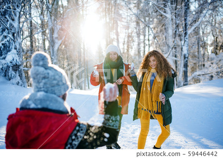 Group of young friends on a walk outdoors in snow in winter forest, having fun. 59446442