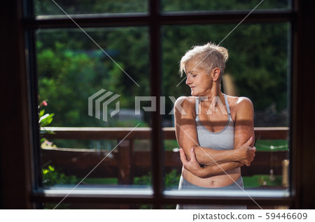A senior woman with sports bra standing outdoors on a terrace in summer. A senior woman with sports bra standing outdoors on a terrace in summer. 59446609