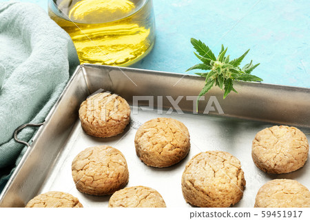 Cannabis butter cookies with marijuana buds and cannaoil, homemade healthy biscuits in a baking tray Cannabis butter cookies with marijuana buds and cannaoil, homemade healthy biscuits in a baking tray 59451917