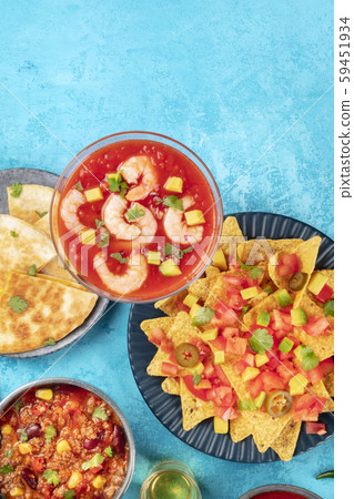 Shrimp cocktail, nachos, and other Mexican food, shot from the top on a blue background with a place Shrimp cocktail, nachos, and other Mexican food, shot from the top on a blue background with a place 59451934
