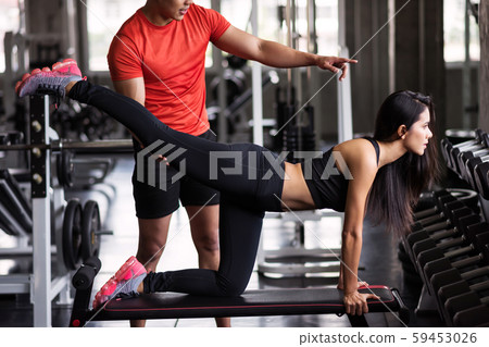 Trainer coach stretching leg to girl in gym Trainer coach stretching leg to girl in gym 59453026