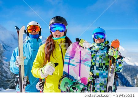 Picture of happy sports woman and men with skis and snowboard standing at ski resort 59456531