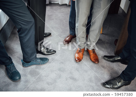 Groom and groomsmen men in blue suits standing in group with closeup of shoes and feet 59457380