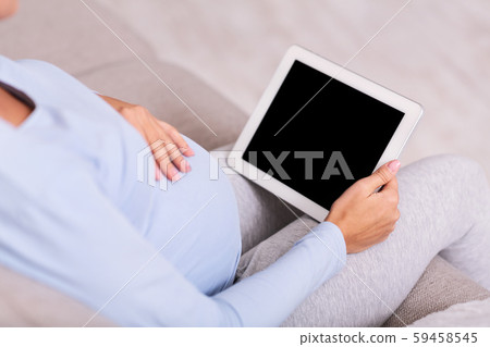 Unrecognizable Expectant Lady Using Tablet Sitting On Couch Indoor, Mockup Unrecognizable Expectant Lady Using Tablet Sitting On Couch Indoor, Mockup 59458545