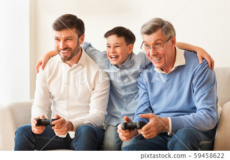 Elderly Man, Mature Son And Grandson Playing Videogame At Home Elderly Man, Mature Son And Grandson Playing Videogame At Home 59458622
