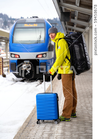 Tourist looking at camera with blue suitcase at station waiting for train 59458678