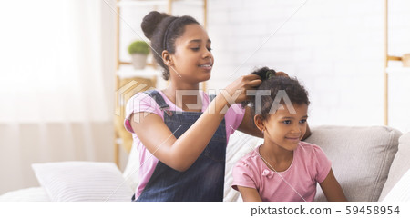 Cheerful afro girl making hairdo to her baby sister 59458954
