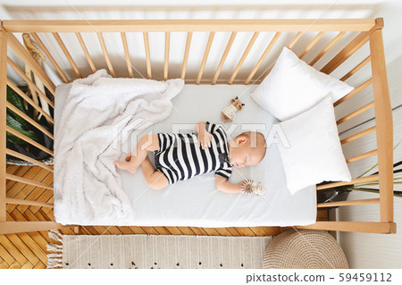 Lovely newborn baby sleeping on back in wooden cot Lovely newborn baby sleeping on back in wooden cot 59459112