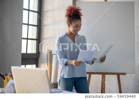 Designer standing near drawing easel and looking at sketches 59459440