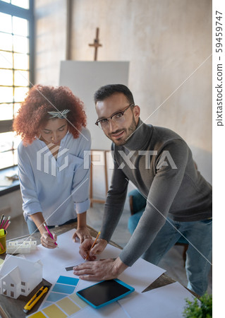 Dark-eyed interior designer making sketches with colleague Dark-eyed interior designer making sketches with colleague 59459747