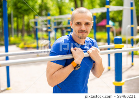 Athletic man leaning on bars and looking in camera Athletic man leaning on bars and looking in camera 59460221