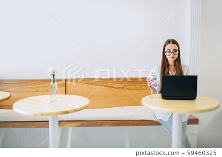 Young business woman working with laptop in a cafe. 59460325