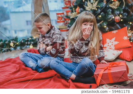 Greedy sister has stolen brother's present and looks at the camera with cunning face expression 59461178