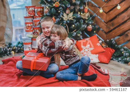 Image of brother and sister in santa hats, tenderly embracing, sharing Christmas presents over Image of brother and sister in santa hats, tenderly embracing, sharing Christmas presents over 59461187