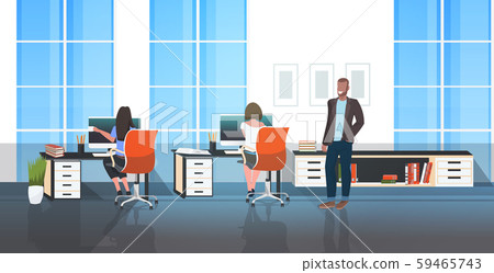 male boss walking through the office and controlling female workers sitting at workplace modern male boss walking through the office and controlling female workers sitting at workplace modern 59465743