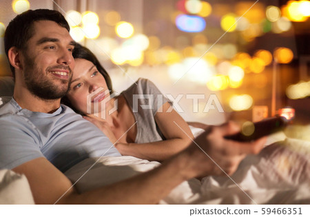 happy couple watching tv in bed at night at home happy couple watching tv in bed at night at home 59466351