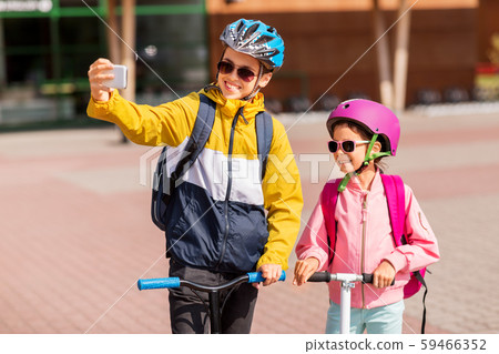 happy school kids with scooters taking selfie 59466352