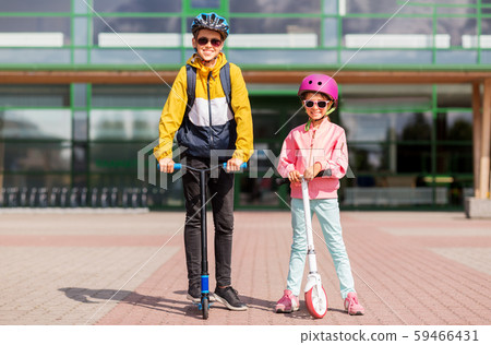 happy school children in helmets riding scooters 59466431