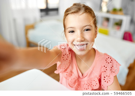 girl taking selfie and showing tongue at home 59466505