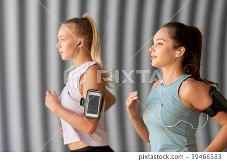 young women with earphones and smartphones running young women with earphones and smartphones running 59466583