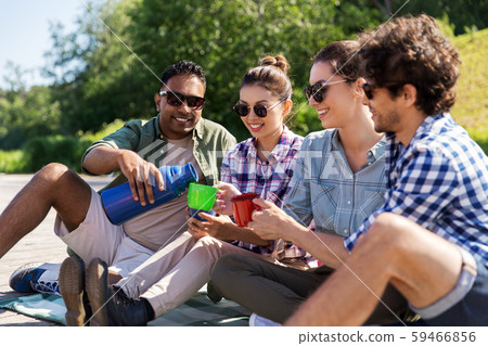 happy friends drinking tea from thermos in summer 59466856