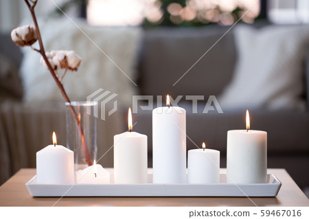 burning white candles on table at cozy home 59467016