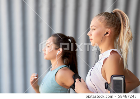 young women with earphones and smartphones running 59467245