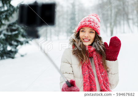 young woman taking selfie by monopod in winter 59467682