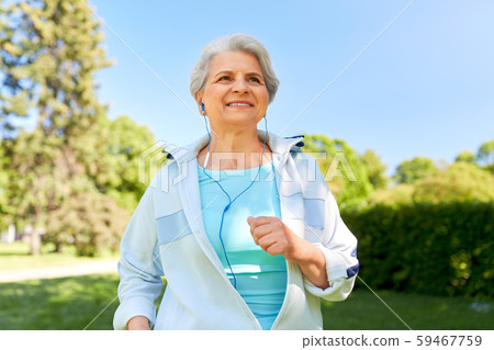 senior woman with earphones running in summer park 59467759