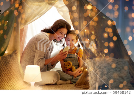 happy family with smartphone in kids tent at home happy family with smartphone in kids tent at home 59468142