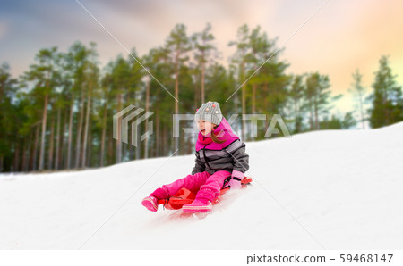 happy little girl sliding down on sled in winter happy little girl sliding down on sled in winter 59468147