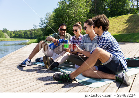 happy friends drinking tea from thermos in summer 59468224