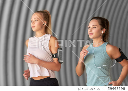 young women with earphones and smartphones running 59468396