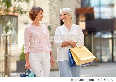 senior women with shopping bags walking in city 59468429
