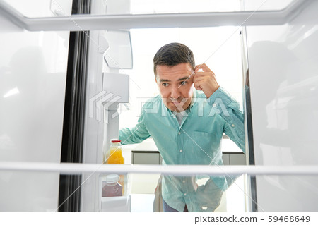 man looking for food in empty fridge at kitchen 59468649