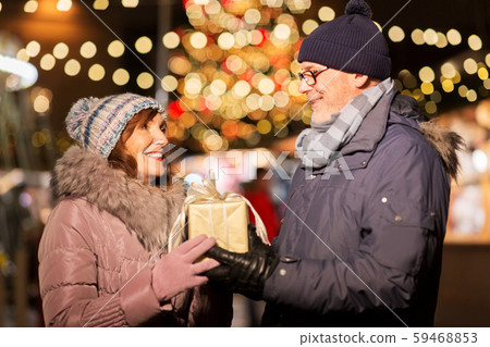 happy senior couple with gift at christmas market happy senior couple with gift at christmas market 59468853