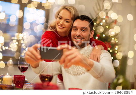 happy couple taking selfie at christmas dinner 59468894
