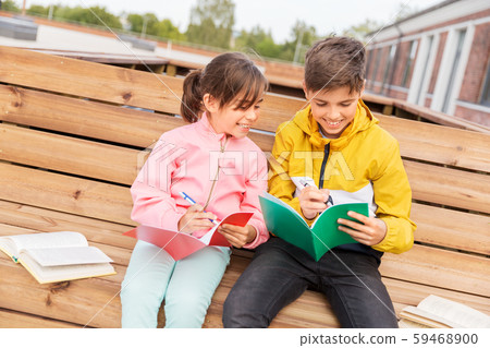 school children with notebooks sitting on bench school children with notebooks sitting on bench 59468900